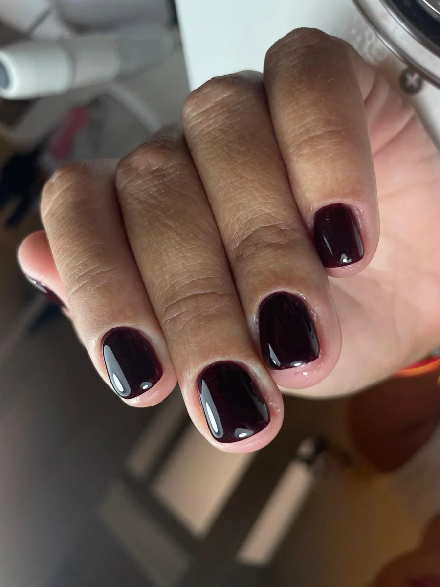Manicura semipermanente en tono burdeos oscuro con acabado espejo