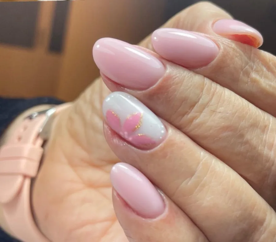 Uñas almendra en rosa nude con diseño floral y detalle dorado